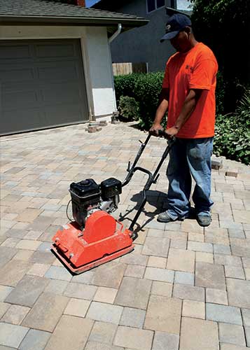 Vibrating the pavers with plate compactor